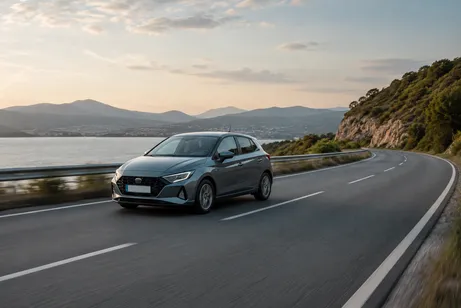 A car driving on a coastal road at sunset