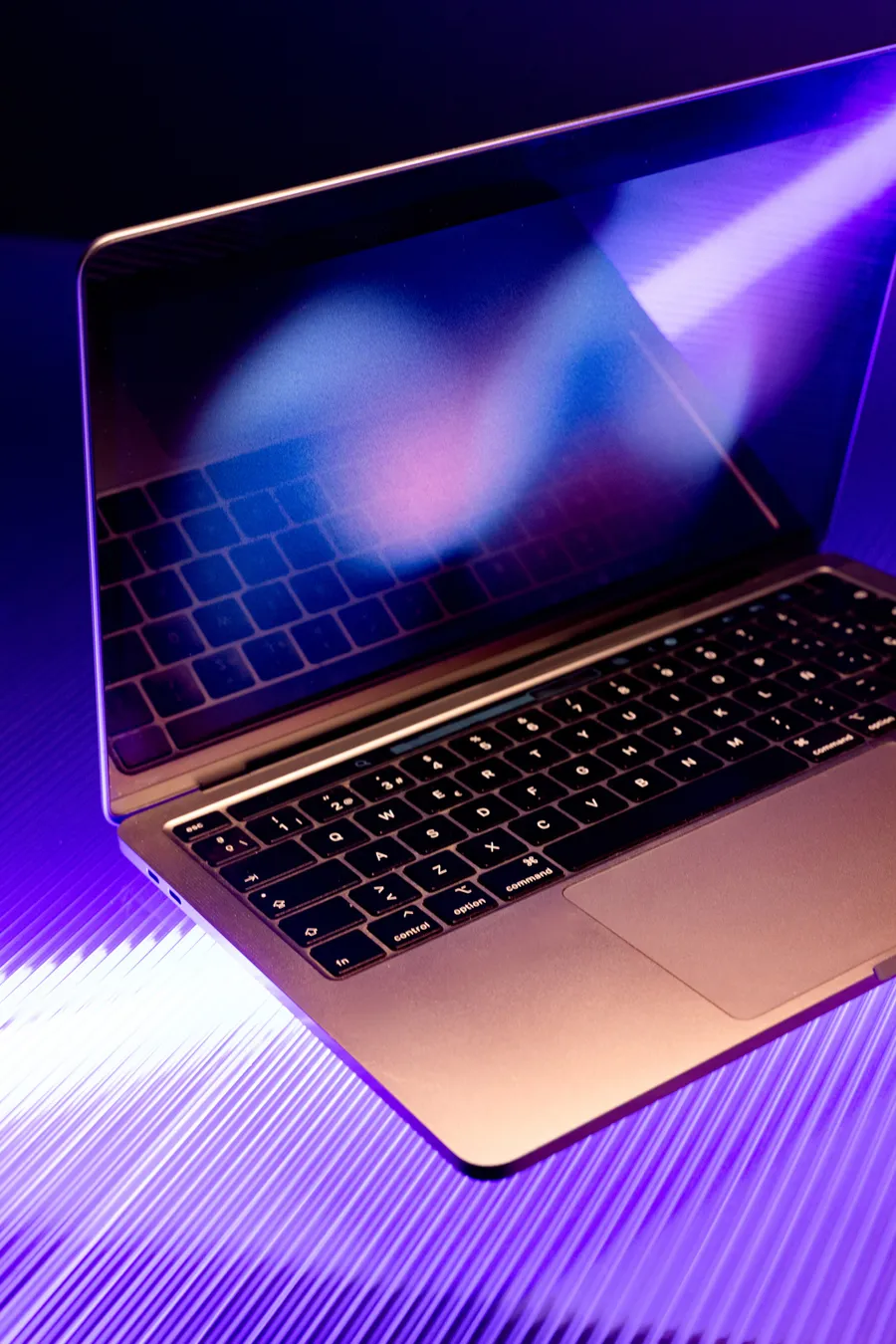 An open laptop with a colourful screen in violet light